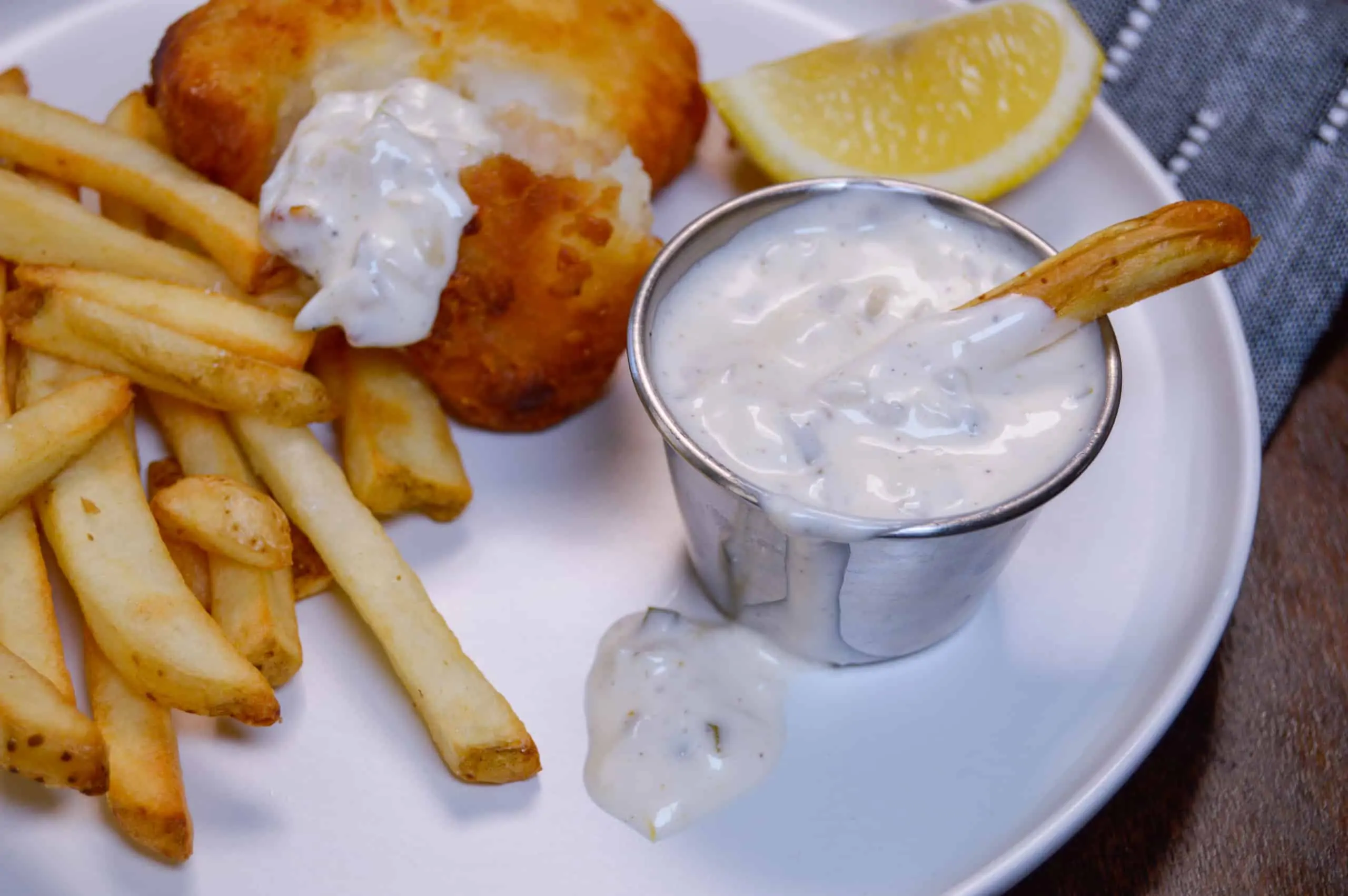 Easy Tartar Sauce with Fry dipped in ramekin, fries on side with dipped fish and a lemon wedge