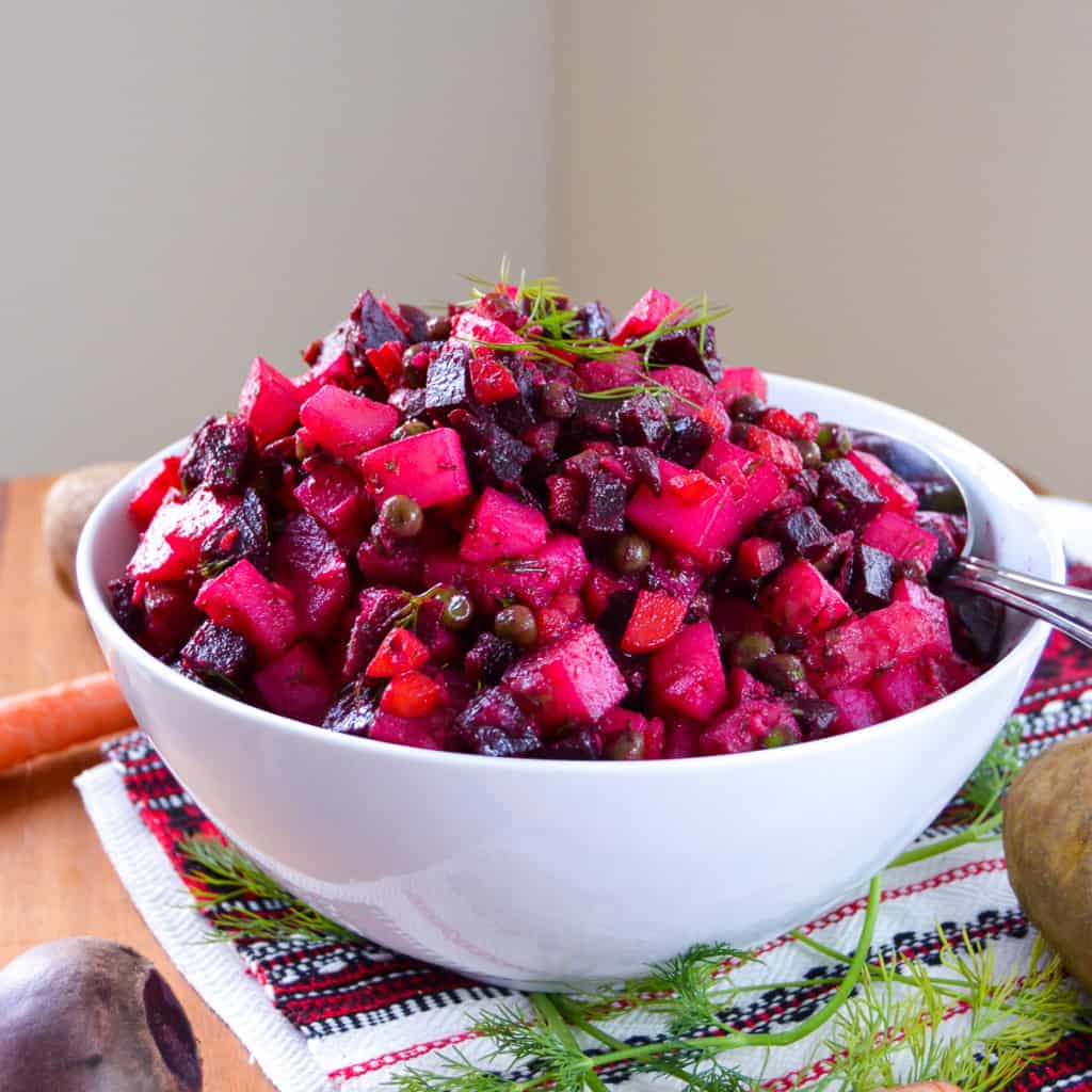 Vinegret Russian Ukrainian beet Salad in white large serving bowl with potato, beet, carrot, and dill