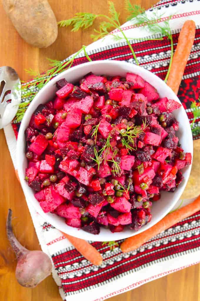 Vinegret in White Bowl with carrots, a beet & serving spoon, on a slavic table runnner