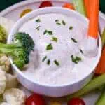White bowl of Homemade Ranch Dip with carrot & broccoli dipped with more vegetables surrounding bowl & chives sprinkled on top