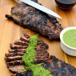 Easy grilled Skirt Steak with chimichurri sauce on top with red wine and knife in background