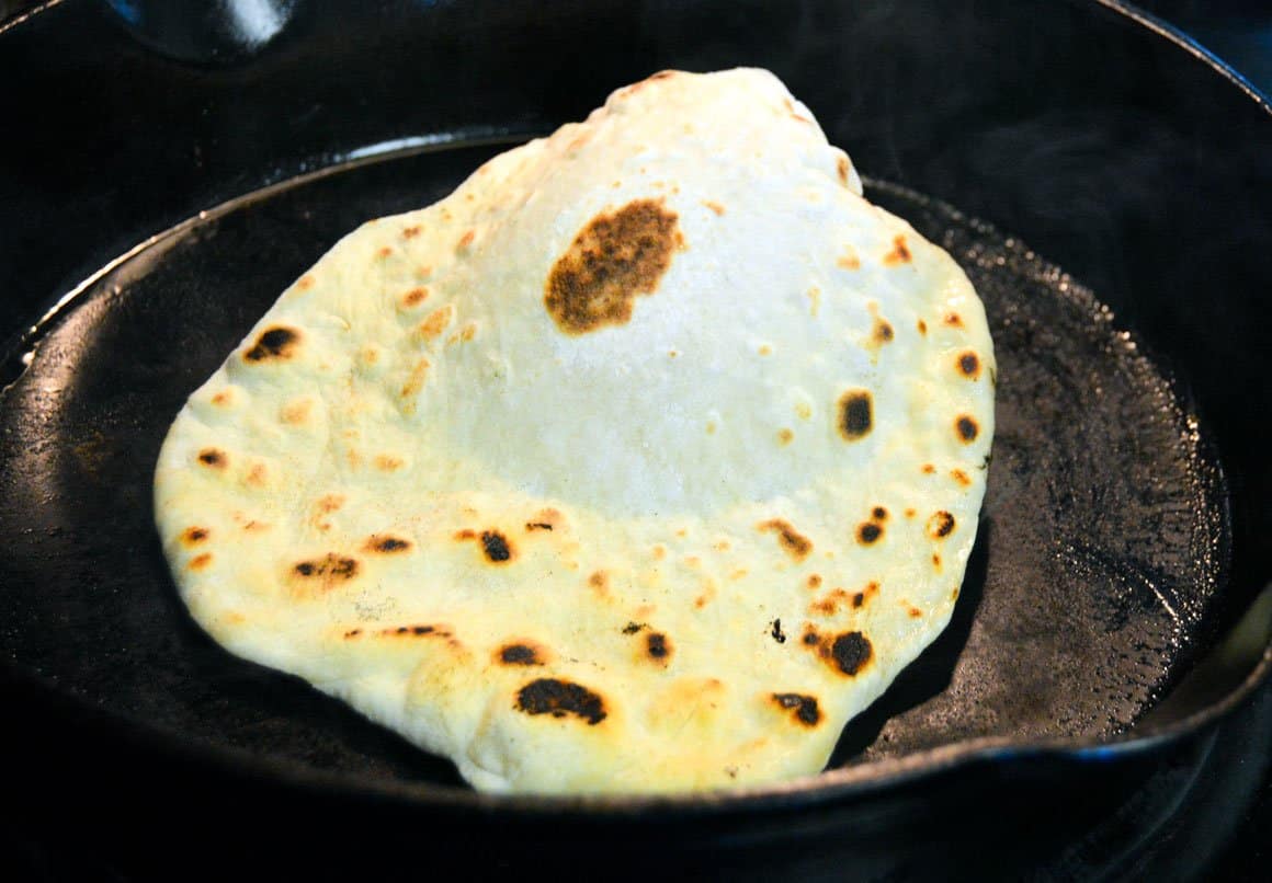 Homemade Pita Bread puffing up in cast iron skillet
