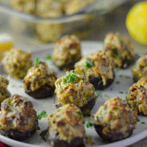 Italian Sausage Stuffed Mushrooms with parsley and lemon zest on white plate