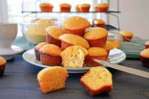 Mini Cornbread muffins on a plate, some cut with butter and more in the background
