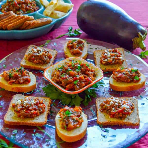 Roasted Red Pepper & Eggplant Spread on Little toasts with parsley on top and dip and eggplant in background