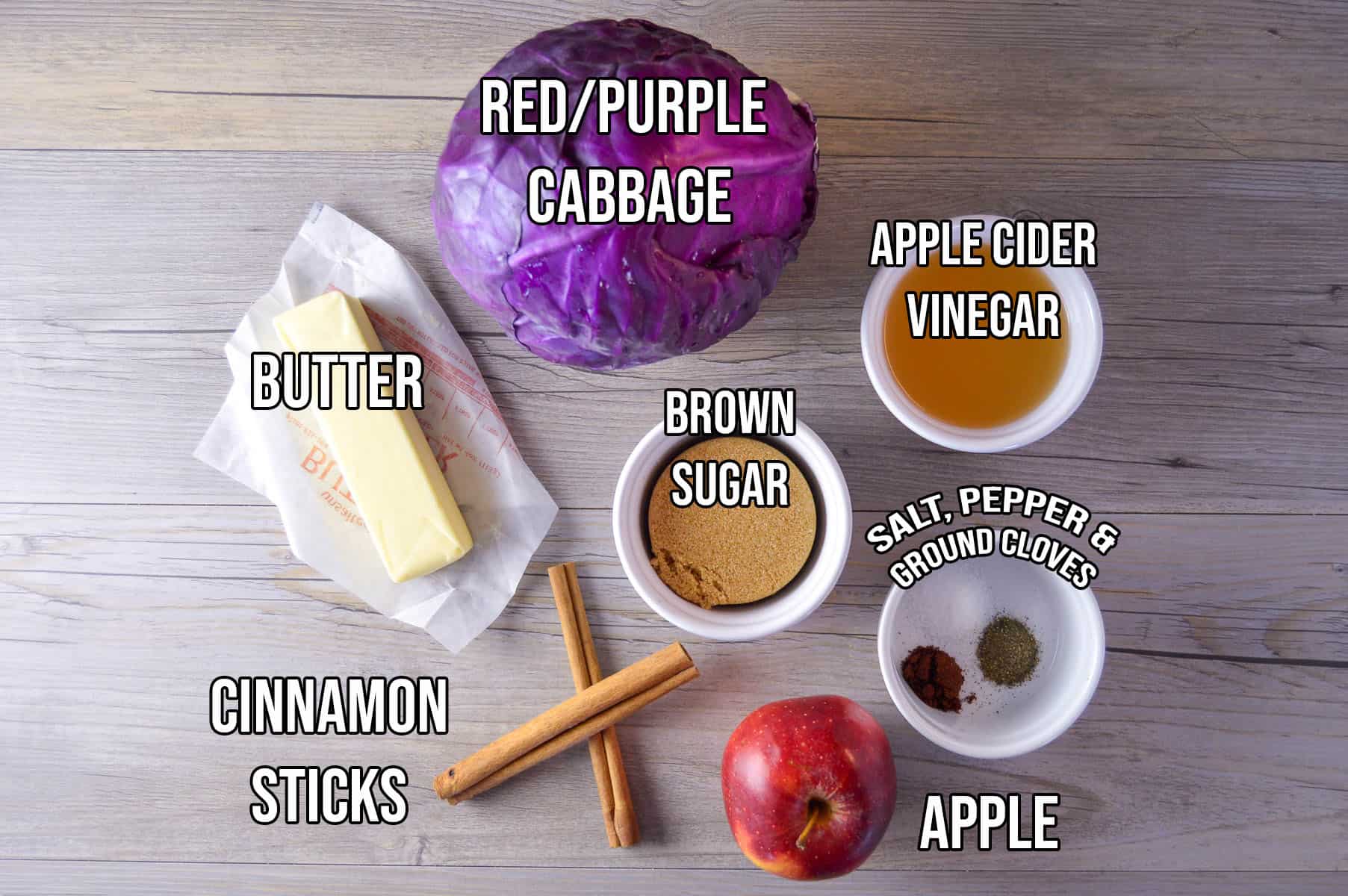 Sweet Simple Braised Red Cabbage Ingredients shown on wooden board: red cabbage, butter, brown sugar, apple cider vinegar, cinnamon sticks, salt, pepper, cloves