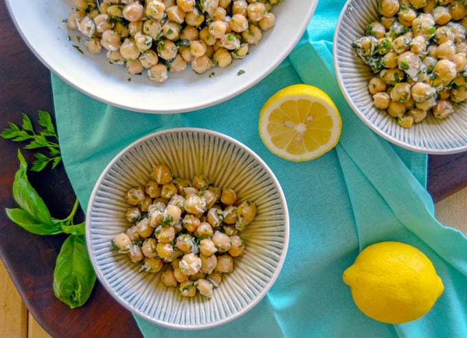 Lemon & Fresh Herb Chickpea Salad in serve bowl and individual bowls with lemon and herbs
