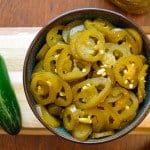 Quick Pickled Jalapenos in bowl on wooden board with jalapeno on the side