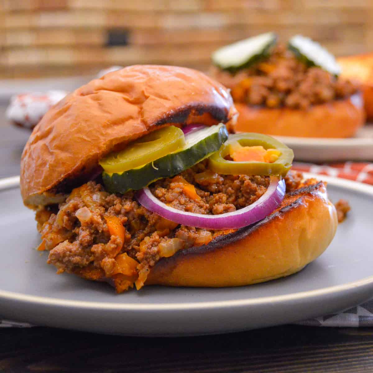 Instant Pot Sloppy Joes with pickles, red onion and pickled jalapenos up close side view
