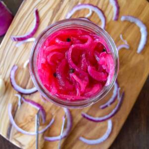 Quick pickled Red Onions with raw red onion and tongs