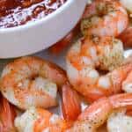 Up close shot of roasted shrimp with cocktail sauce in a small bowl