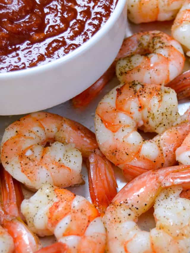 Up close shot of roasted shrimp with cocktail sauce in a small bowl