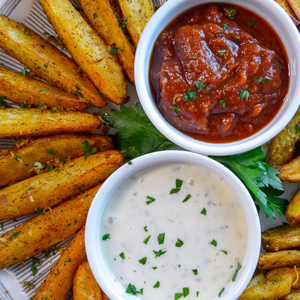 potato wedges pinterest image on plate with ramekins and dip, shot from above
