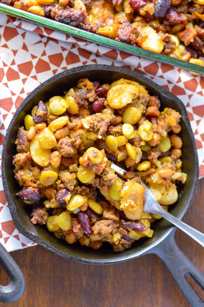 Cooked Beans Side Dish in skillet with fork on red and white napkin with glass casserole dish