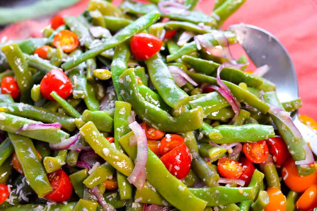 Up close look at salad with green beans, cherry tomatoes, red onion and parmesan cheese with napkin in background
