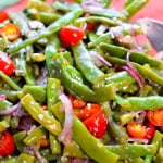 Up close look at salad with green beans, cherry tomatoes, red onion and parmesan cheese with napkin in background