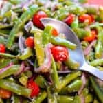 Garden Fresh Green Bean Salad Up close on a serving spoon with red onion, tomatoes and parmesan cheese