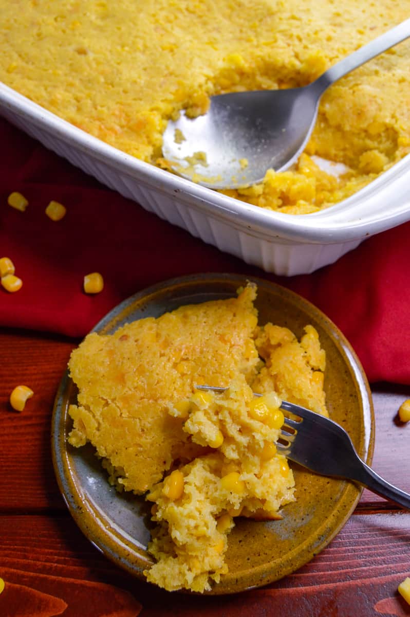 Southern Corn Pudding Casserole on small plate with fork and baking dish with casserole in the background