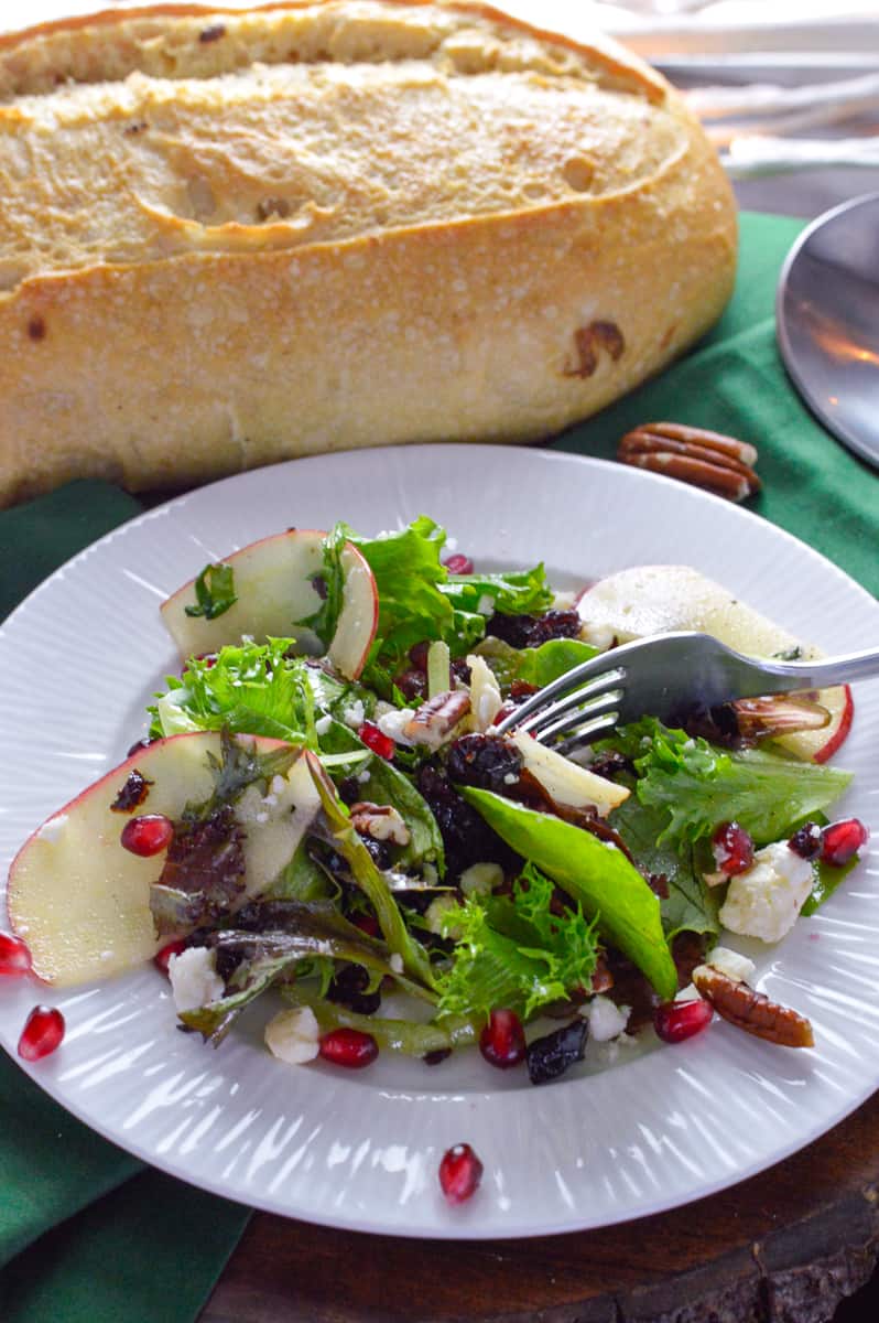Green Holiday Salad with apple, pomegranate with bread loaf in background