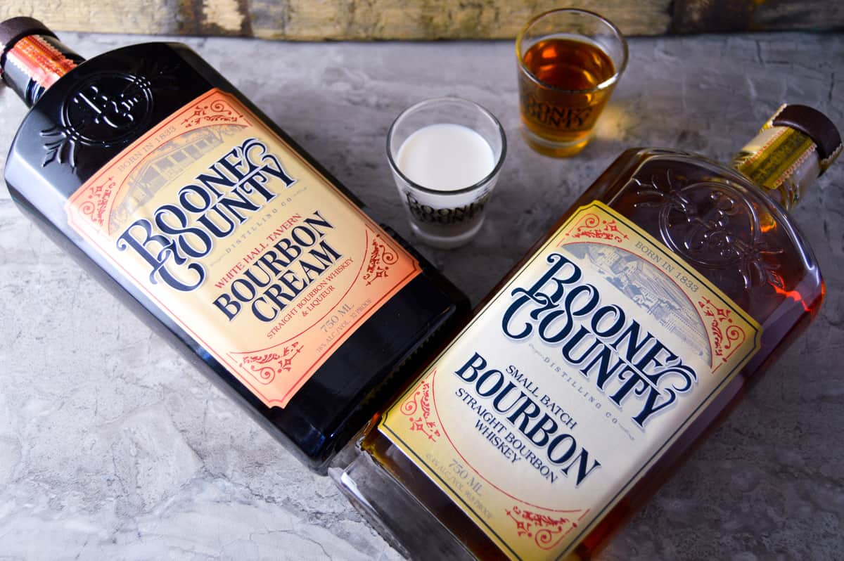 Bottle of Boone County Bourbon Cream and Boone County Small Batch Bourbon on the counter next to shots of both alcohols