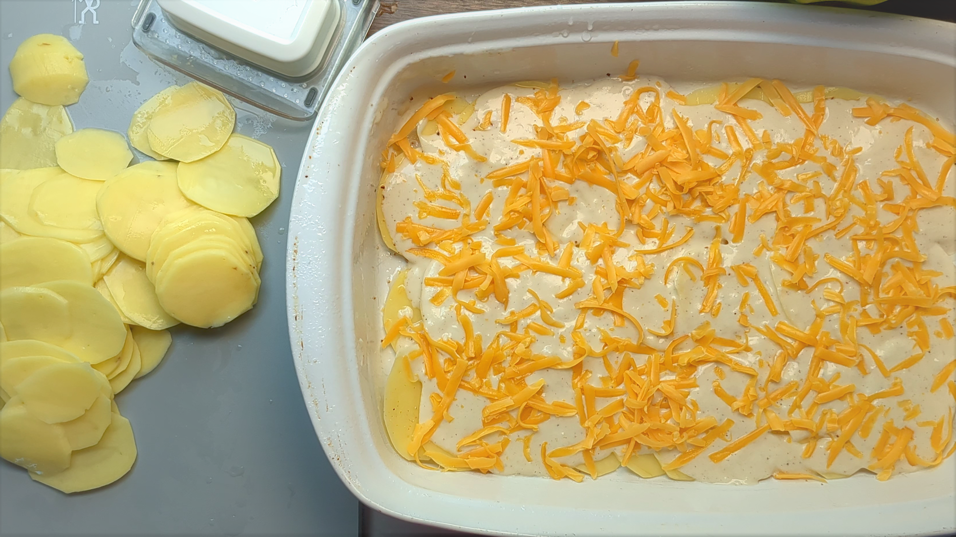 Partially put together Au Gratin dish with mandoline sliced potatoes on side below mandoline slicer