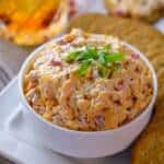 Southern Pimento Cheese Spread in white bowl with crackers and glass of bourbon