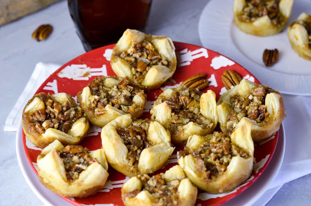 pecan puffs on red and white nutcracker Christmas plate with maple syrup and another white plate with puffs in the background 