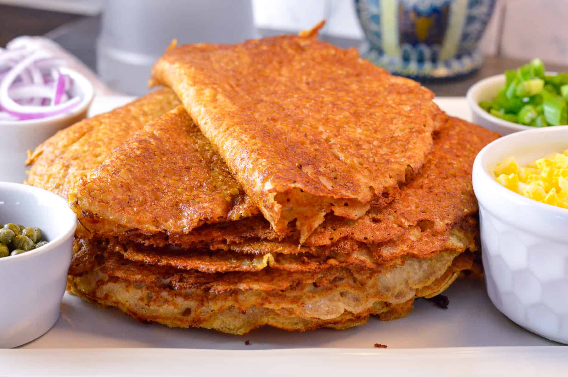 Stack of blini with fillings on the side, vodka bottle and nesting doll in background