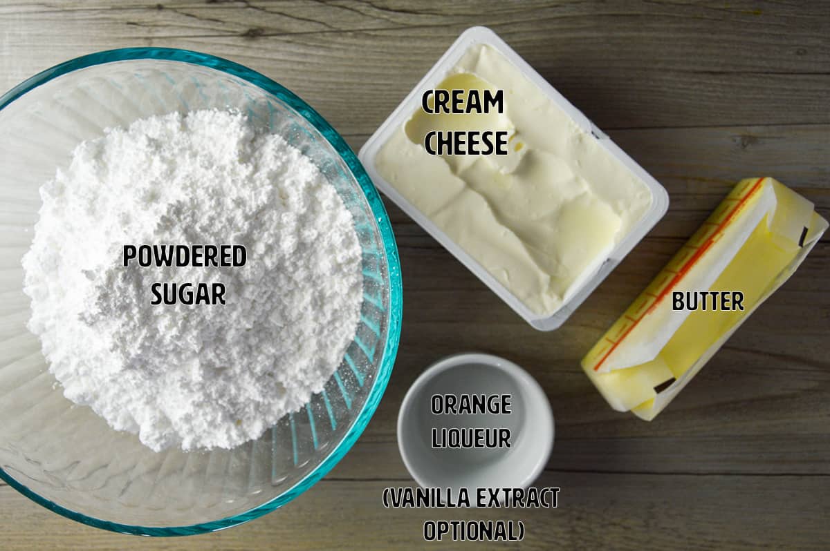 Ingredients shown on wooden table for orange carrot cake cream cheese frosting: powdered sugar, cream cheese, butter, orange liqueur and optional mention of vanilla extract