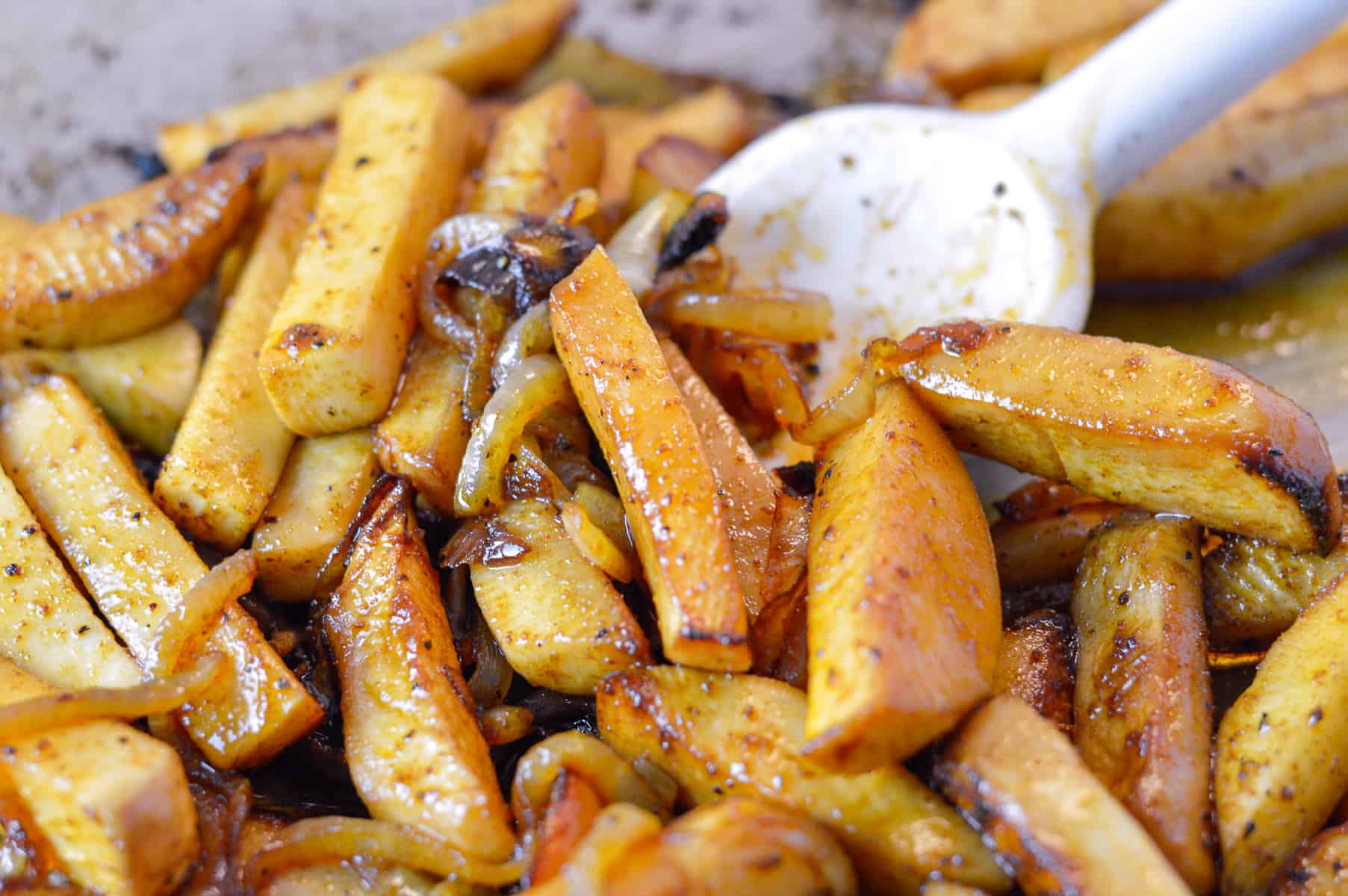 Up close look at balsamic turnips after roasting in the smoker pellet grill with white spatula spoon