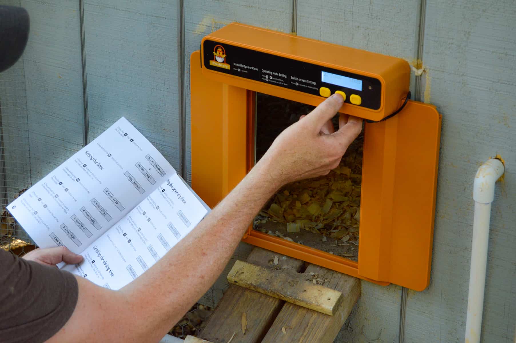 Adjusting settings on yellow Automatic chicken coop door just installed. 