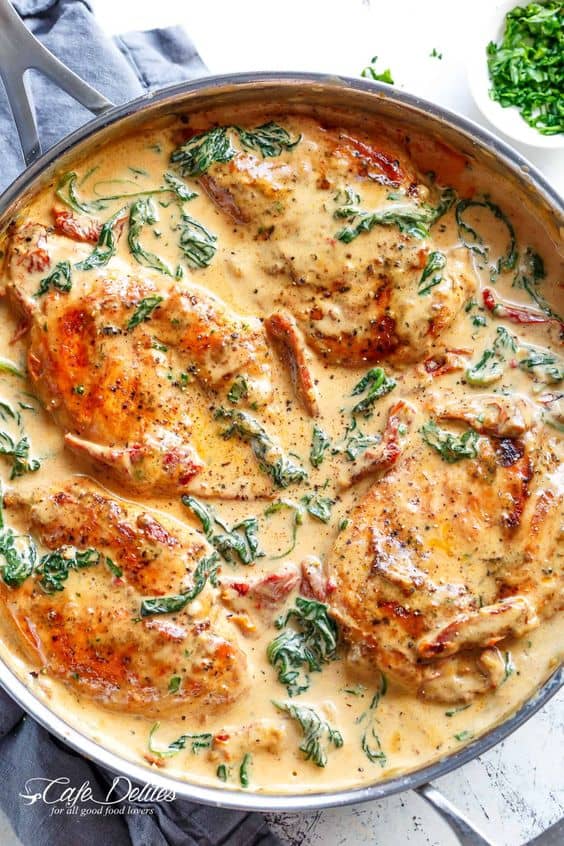 Creamy Tuscan Chicken Cafe Delites  with chicken in a skillet with a spinach cream sauce Pinterest Pin 