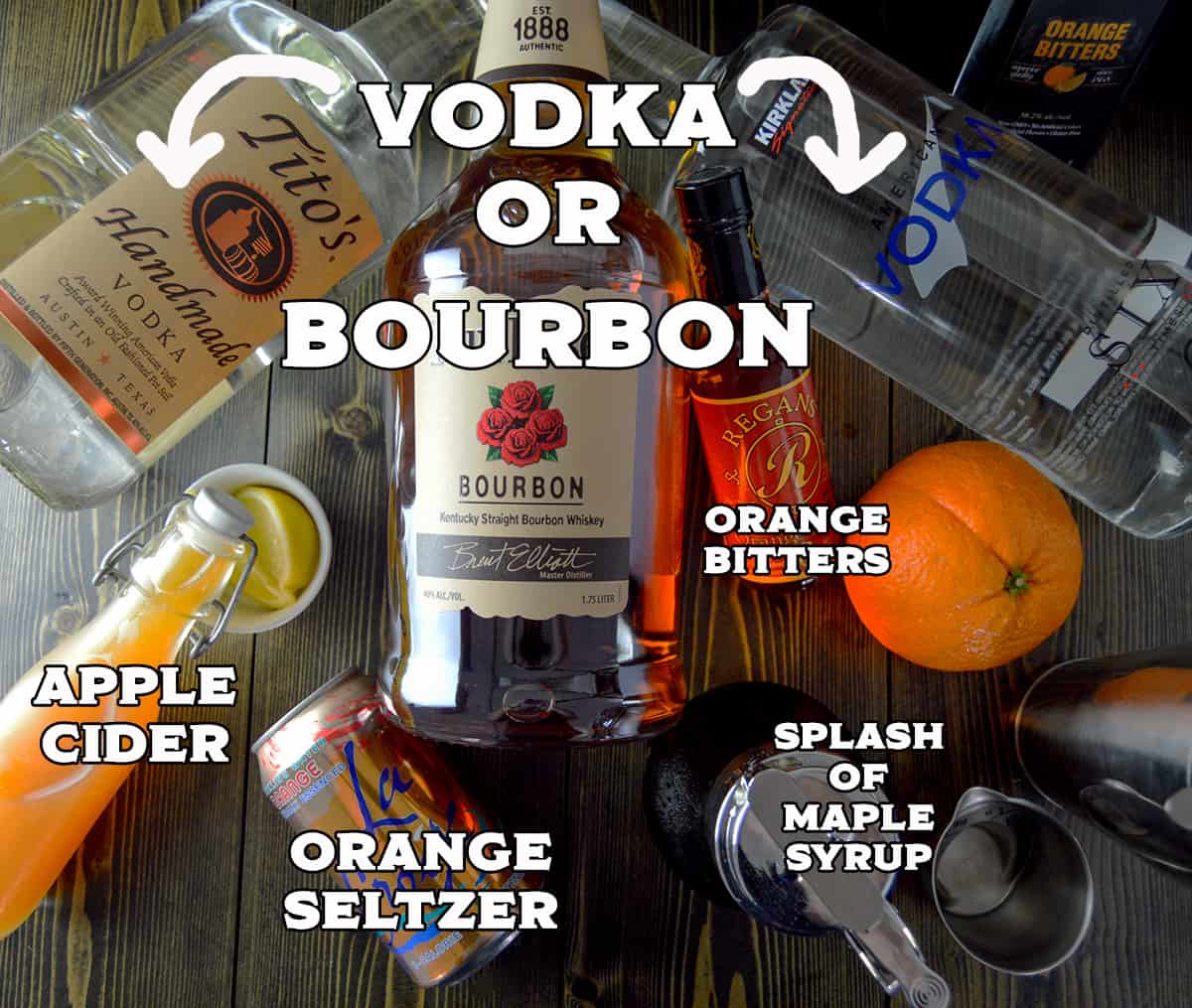 Ingredients shown on wooden counter for apple cider cocktail: 2 vodkas, bourbon, orange, shaker, apple cider, 2 bottles of bitters