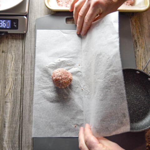 sausage ball mixture placed on wax paper to smash