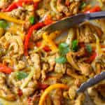 Sheet Pan chicken fajitas on gold baking sheet with silver tongs