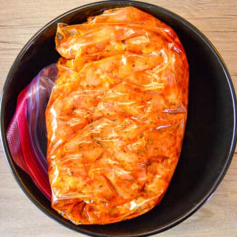 chicken with fajita marinade closed up in zip top bag with marinade mixed into it in black bowl