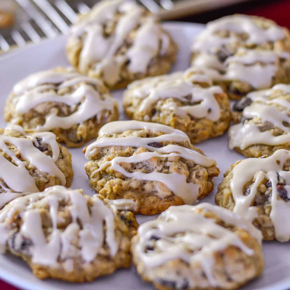 oatmeal raisin cookies with maple glaze drizzled on top on white plate atop a red napkin