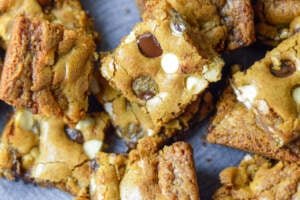 Chocolate chip blondies with dark and white chips on a grey ceramic plate randomly stacked and dispersed