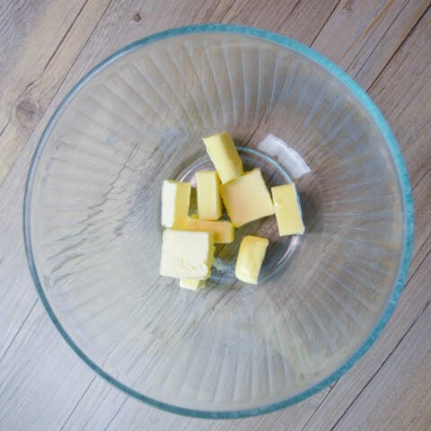 cut up butter ready to melt in a glass mixing bowl